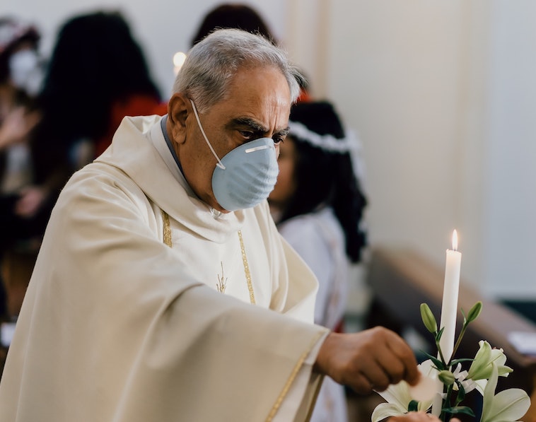 Catholic priest wearing a face mask during Holy Communion. 