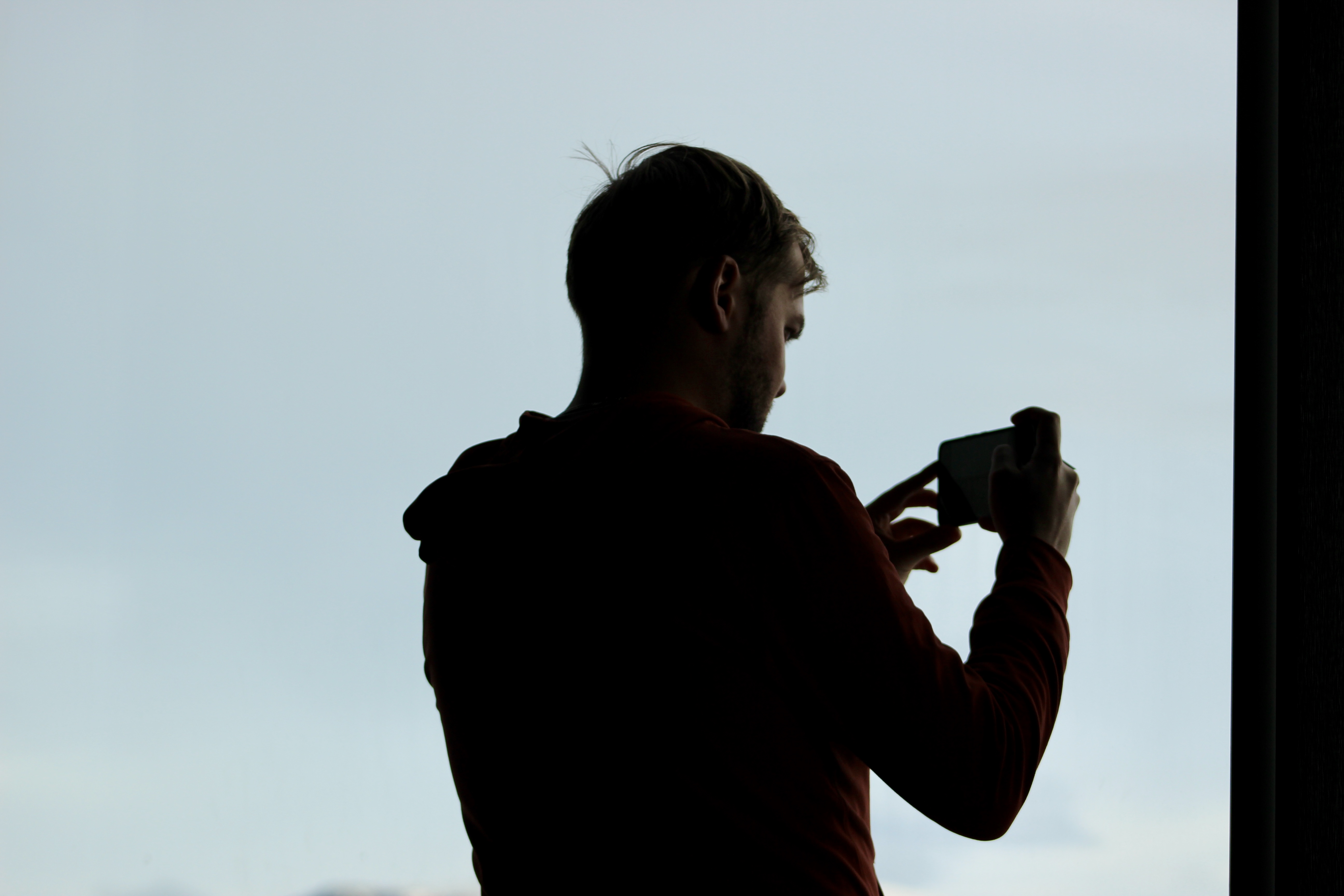 A man taking a photo out a bright window creates a silhouette of the man