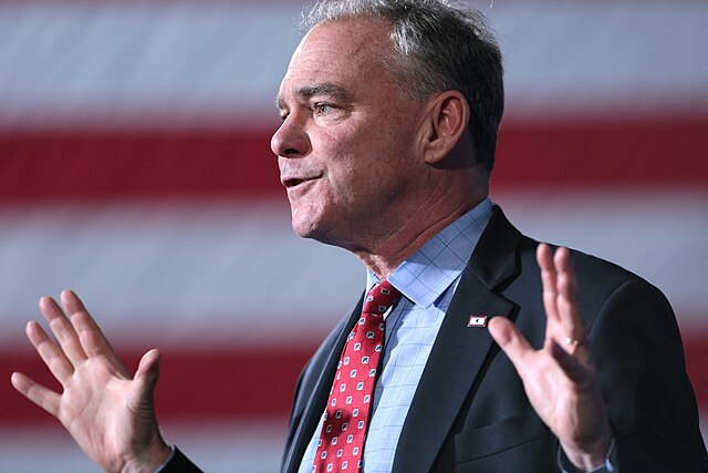 Tim Kaine stands in front of an American flag