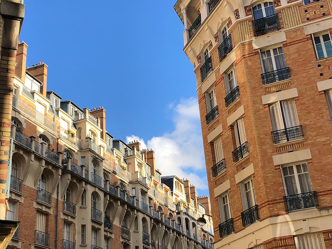 Looking up at red brick buildings which line a Paris street