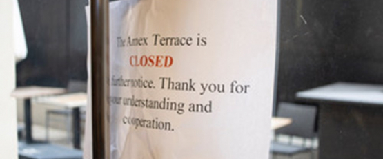 A sign is taped to an exterior facing glass door that explains the terrace is closed