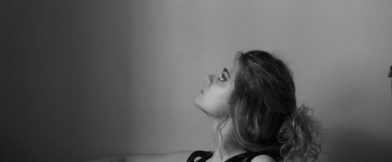 A blond model sitting on a chair in an indoor setting