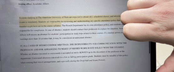 Student dissapproving of attendance policy by putting a thumbs down in front of photo of the policy