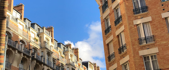 Looking up at red brick buildings which line a Paris street