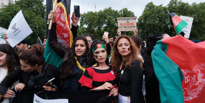 Afghan protesting against the Taliban. They are carrying the Afghan flag, and signs.