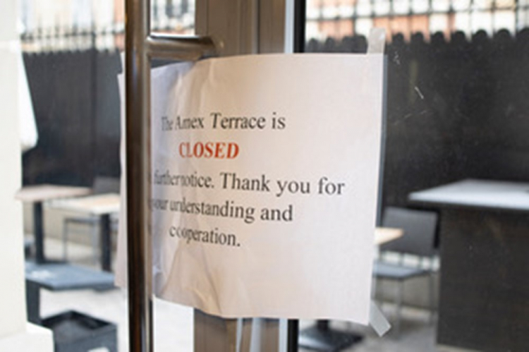 A sign is taped to an exterior facing glass door that explains the terrace is closed